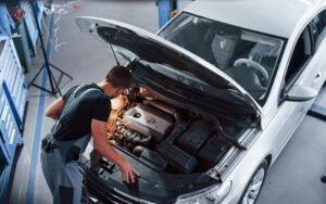 Under,The,Hood.,Man,In,Grey,Uniform,Repairs,White,Automobile