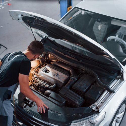 Under,The,Hood.,Man,In,Grey,Uniform,Repairs,White,Automobile